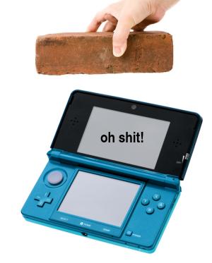 A hand preparing to drop a brick onto a Nintendo 3DS system. The 3DS's top screen says, Oh Shit!