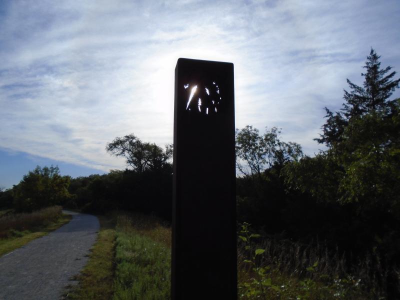 Sunlight coming through a stamped design on a metal trail marker.